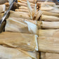 Stacks of green Chile tamales on a stainless steel trays.